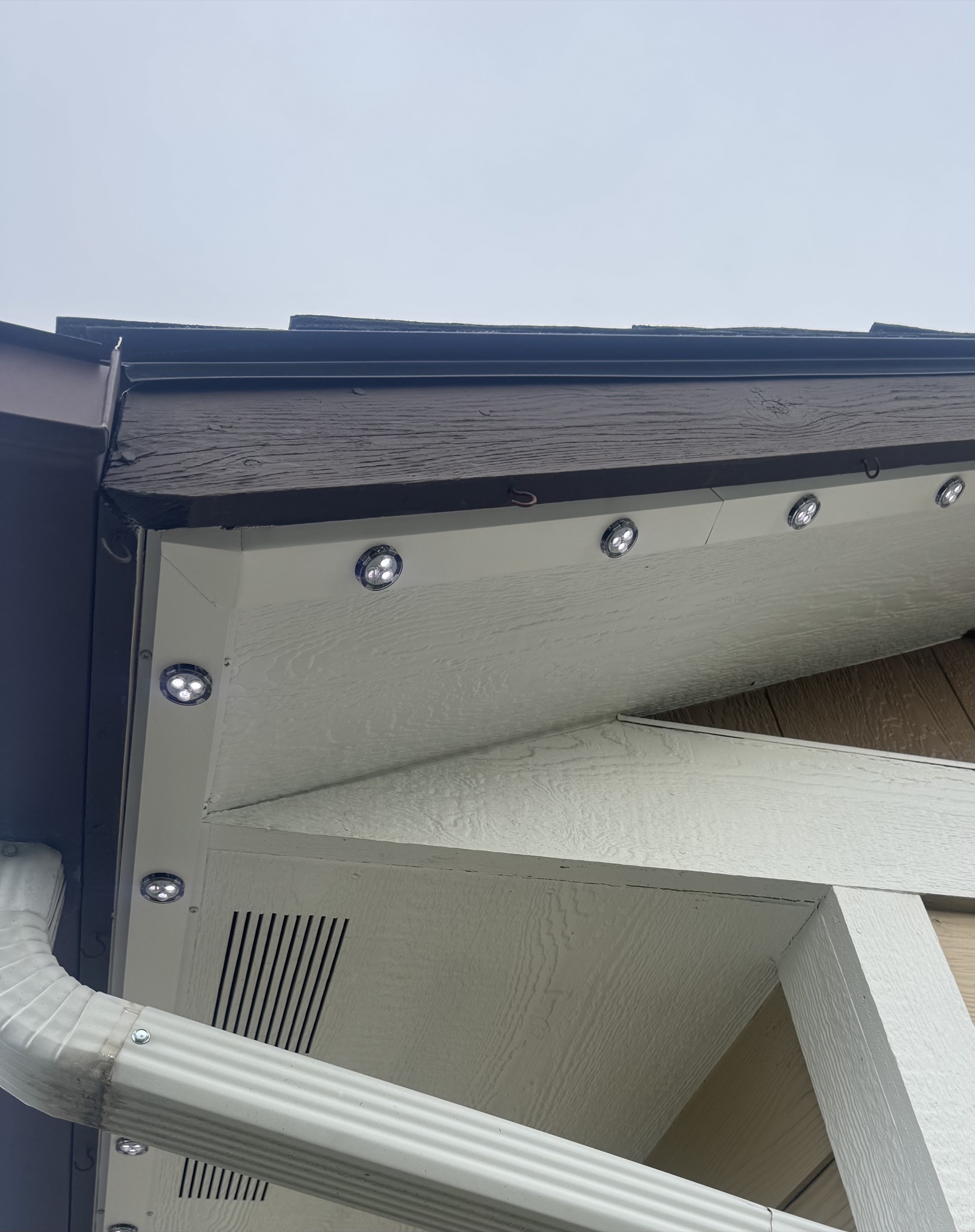 Close-up daytime view of a low-profile LED fixture mounted flush under a home's eave