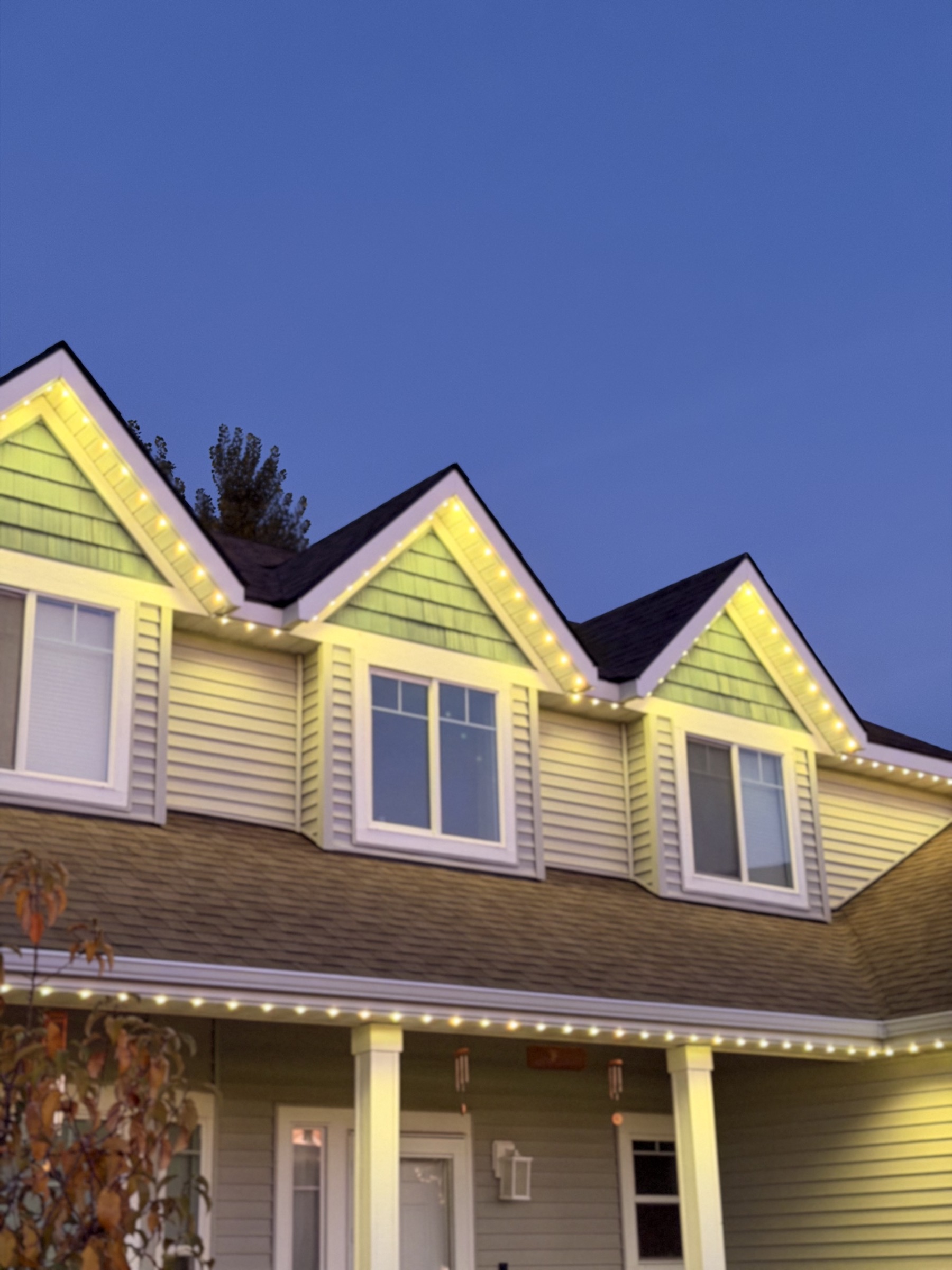 Close-up of a home's gables lit with warm white trim lighting at dusk