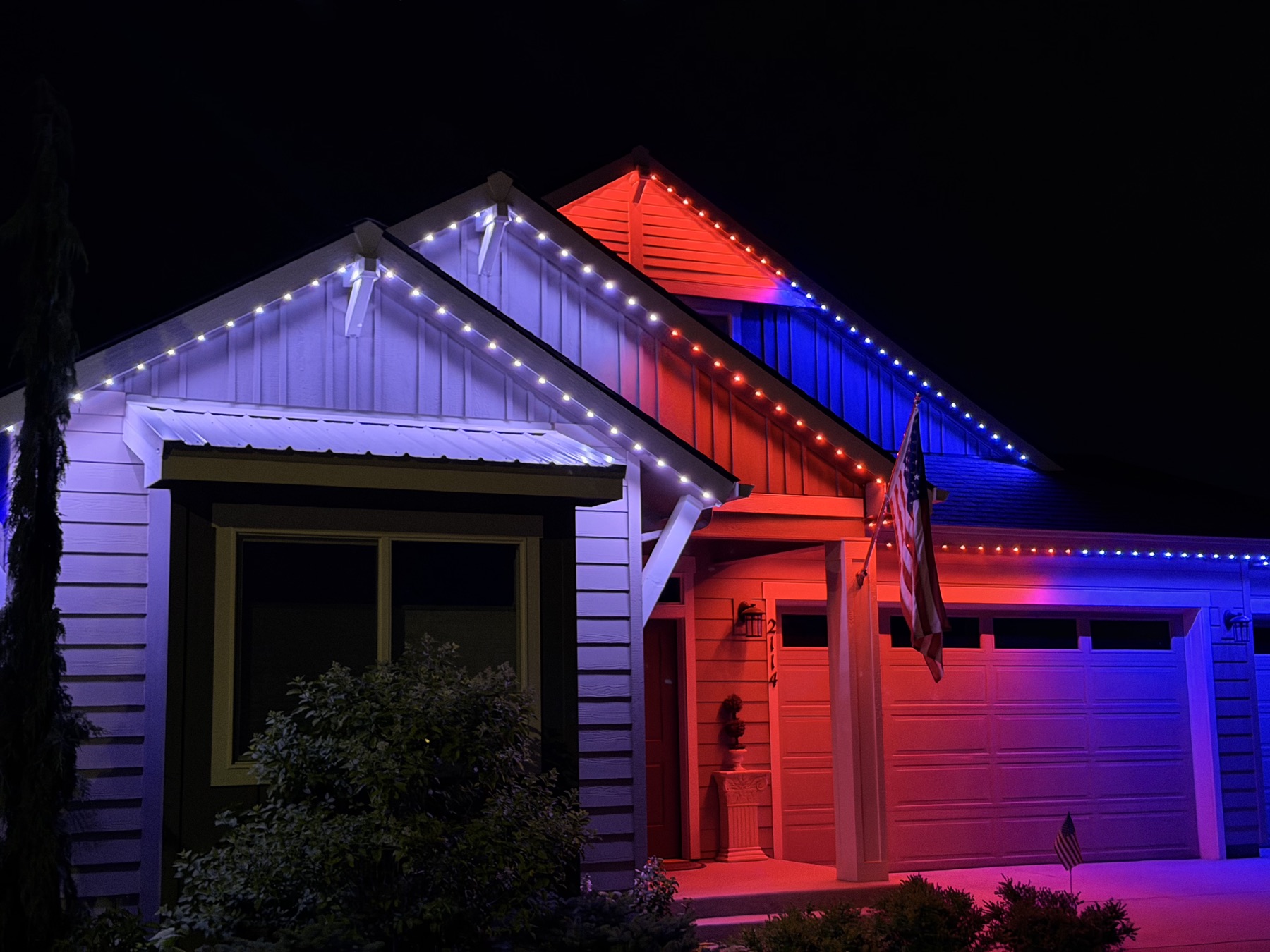 A home's roofline lit in red, white, and blue trim lighting for a holiday