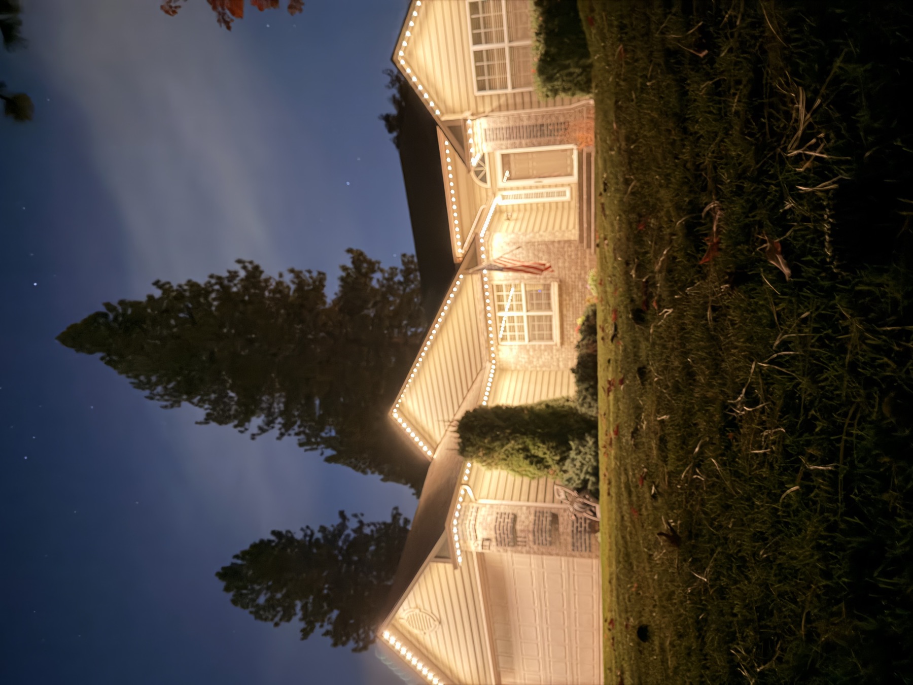 A home's roofline lit with warm white trim lighting on a starry night